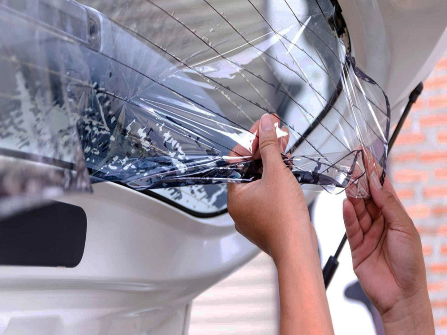 Tint Werkz technician carefully removing old window tint film from a vehicle during professional tint removal service