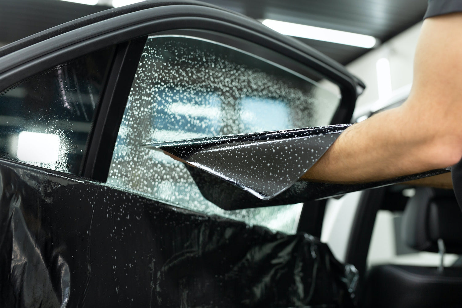 Tint Werkz technician expertly installing automotive window tint with precision and care